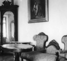 Chorówka, woj. lwowskie. Pałacyk Ignacego Łukasiewicza. Fragment wnętrza z widocznym lustrem, kanapą, stołem i obrazem.